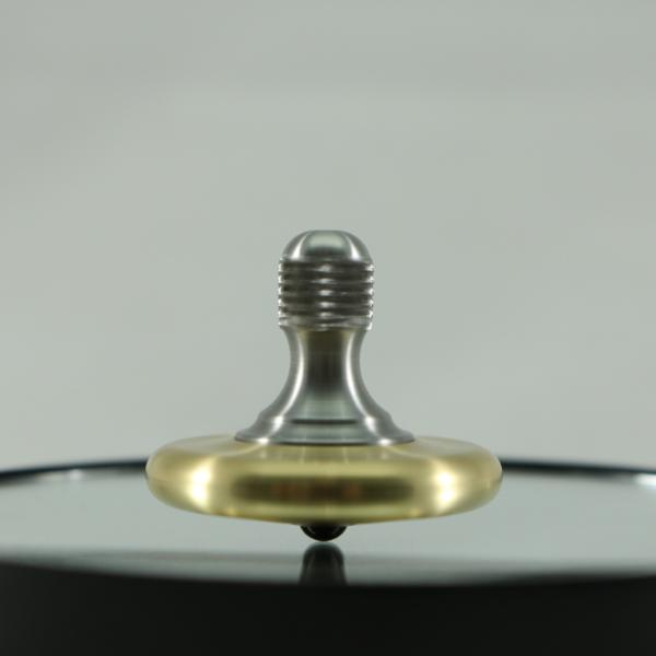 Caught mid spin is the M3 precision meal spinning top by Kemner Design shown here in brushed brass and stainless steel